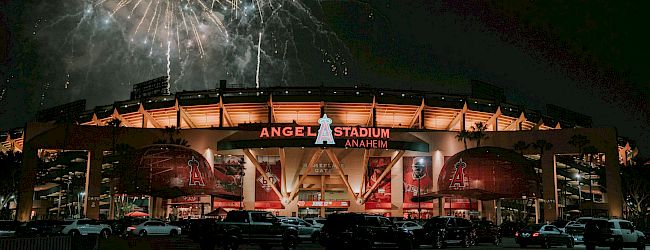 Fireworks explode over Angels Stadium at night, illuminating the arena as crowds gather for a show.