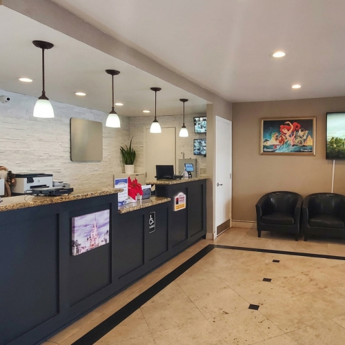 A modern cafe or fast-casual restaurant with a dark blue counter, hanging lights, chalkboard/menu boards, and a bright seating area in the background, tidy and inviting.